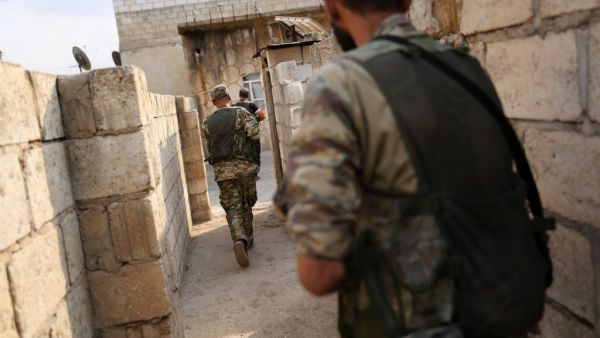 Turkey-backed Syrian fighters leave a house that they are using as a postition in the Syrian border town of Ras al-Ain (AFP)