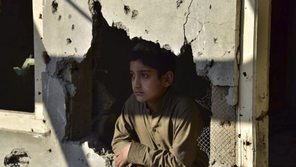 A Kashmiri boy looks out from his damaged family house after cross border shelling in Jura, a village of Neelum valley in Pakistan-administered Kashmir  (AFP)
