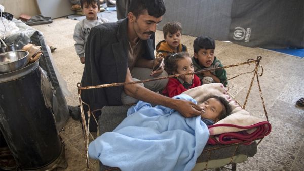 A Displaced Syrian man soothes a baby inside a school turned into a shelter for people displaced by the war, in the northeastern Syrian town of Hasakeh, on October 25, 2019. (AFP/ File Photo)