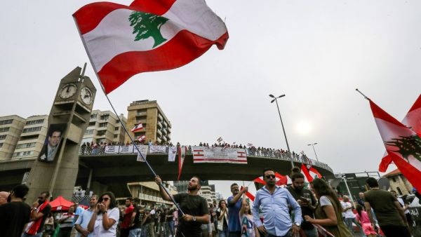 A man waves a Lebanese national flag during a demonstration on the highway that links the capital Beirut to the northern city of Tripoli, in the area of Jal el-Dib in the northeastern outskirts of the capital, on October 26, 2019 on the tenth day of protest against tax increases and official corruption. (JOSEPH EID / AFP)