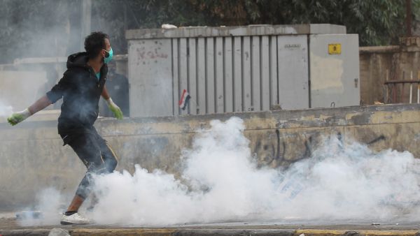 An Iraqi demonstrator runs through a cloud of tear gas during continuing anti-government protests in the centre of Baghdad on October 27, 2019. The Iraqi capital and south have been rocked by a second wave of demonstrations since October 24, with protesters persevering despite tear gas, curfews and violence that has left over 60 dead. (AFP/ File Photo)