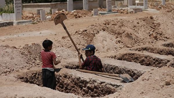 Jawad, eight, and Yazan, 15, should be in school, but they spend their days working as gravediggers and tending to dead bodies with their father Ghassan. (Save The Children)