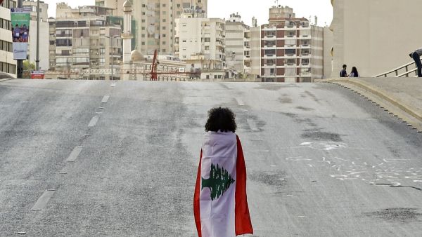 A Lebanese woman protester walks draped in a national flag along the Fuad Chehab avenue, near the Martyrs' Square, in the centre of the capital Beirut on October 29, 2019. (AFP/ File Photo)