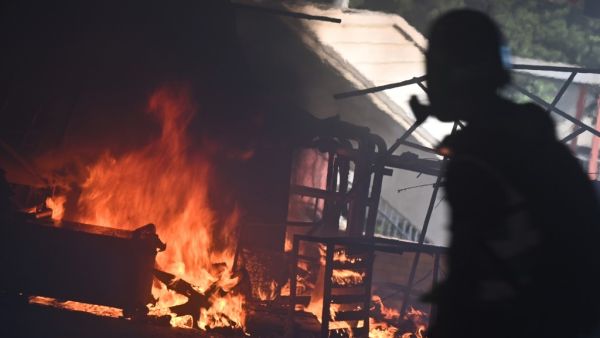 A man walks past burning barricades at the entrance the Hong Kong Polytechnic University during a protest on November 11, 2019. A Hong Kong police officer shot at masked protesters -- hitting at least one in the torso -- during clashes broadcast live on Facebook, as the city's rush hour was interrupted by protests. (Philip FONG / AFP)