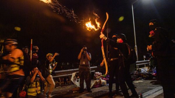 A protester releases a fire arrow with his bow to light a barricade at the Chinese University of Hong Kong (CUHK), in Hong Kong early on November 13, 2019. Hong Kong pro-democracy protesters fought intense battles with riot police on a university campus and paralysed the city's upmarket business district Tuesday, extending one of the most violent stretches of unrest seen in more than five months of political chaos. Anthony WALLACE / AFP