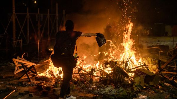 A protester pours petrol onto a burning barricade at the Chinese University of Hong Kong (CUHK), in Hong Kong early on November 13, 2019. Hong Kong pro-democracy protesters fought intense battles with riot police on a university campus and paralysed the city's upmarket business district Tuesday. ( Anthony WALLACE / AFP)