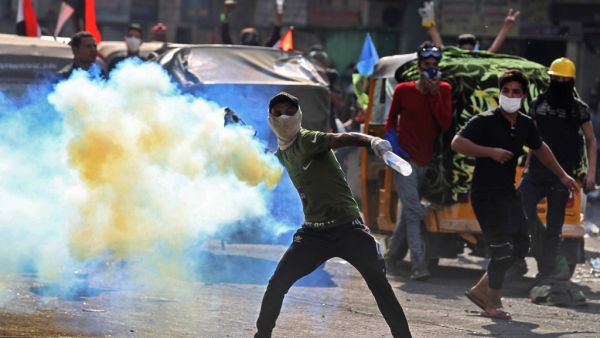 An Iraqi protester throws back a tear gas canister fired by security forces amid clashes at Baghdad's Khallani square during ongoing anti-government demonstrations on November 15, 2019. Iraq's political elite has come under renewed pressure in recent days from both the street and the international community to seriously address calls for reform. AHMAD AL-RUBAYE / AFP