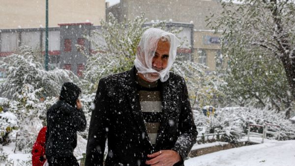 People walk under heavy snow in the Iranian capital Tehran on November 16, 2019. Heavy snowfall blanketed the streets of north Tehran causing traffic chaos and forcing the closure of schools, authorities in the Iranian capital said. Crews of municipal workers were battling to clear roads and pavements in parts of the capital, where snow began falling at the start of the morning rush hour and continued through the day. ATTA KENARE / AFP
