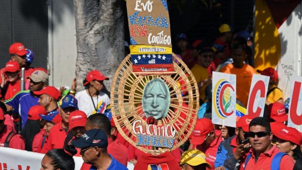 Pro-government supporters hold a sign reading "Evo, Venezuela is with you" and the image of Venezuelan late President Hugo Chavez, during a demo in Caracas, on November 16, 2019. Venezuela's opposition called to protest against President Nicolas Maduro on Saturday, while the government also called on their own supporters to mobilize. (YURI CORTEZ / AFP)