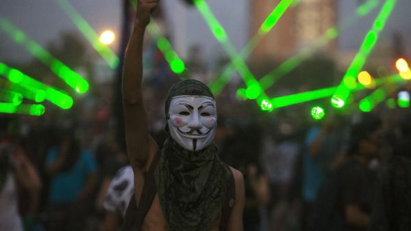 A demonstrator wearing Guy Fawkes mask gestures during a protest against the government, in Santiago on November 18, 2019. (AFP/ File Photo)