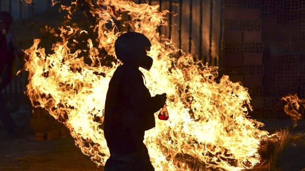 A man walks in front a fire blockade set by supporters of Bolivian ex-President Evo Morales in the outskirts of Sacaba, Chapare province, Cochabamba, on November 18, 2019. Bolivia's interim president said Sunday she will call new elections soon, as the country struggles with violent unrest a week after the resignation of Evo Morales. (RONALDO SCHEMIDT / AFP)