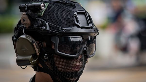 A riot police officer monitors people (not pictured) gathered in the street in support of pro-democracy protesters during a lunch break rally in the Kowloon Bay area in Hong Kong (AFP)