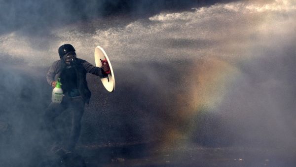 A demonstrator protects himself from the spray of a police water cannon with a makeshift shield during a protest against the government in Santiago on November 26, 2019. (AFP/ File Photo)