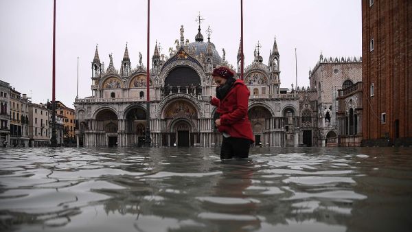 Submerged: A woman crosses the flooded St Mark's Square yesterday morning where Venice's 1,200-year-old basilica (pictured behind her) was flooded by the high tide. (AFP/ File Photo)