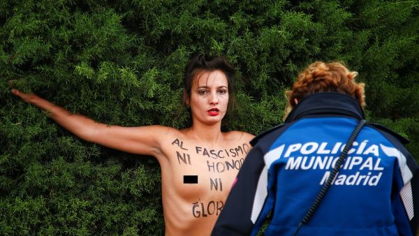'To fascism neither honour nor glory': A topless woman from the feminist action group Femen stands before a police officer in Madrid today as she demonstrates against the supporters of General Francisco Franco (dailymail)