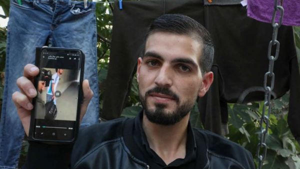 Palestinian Karam al-Qawasmi displays a leaked video showing an Israeli soldier shoot him [AFP/Getty]
