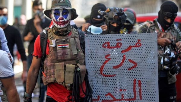 A 23-year-old unemployed Iraqi man, wearing face-paint modeled after DC comic book and film character "The Joker", poses for a picture with a makeshift riot shield bearing text in Arabic reading "Tahrir Shield Division", during an anti-government demonstration in the capital Baghdad on November 22, 2019. (AFP/ File Photo)