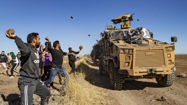 Kurdish demonstrators hurl rocks at a Turkish military vehicle on November 8, 2019, during a joint Turkish-Russian patrol near the town of Al-Muabbadah in the northeastern part of Hassakah on the Syrian border with Turkey. Delil SOULEIMAN / AFP