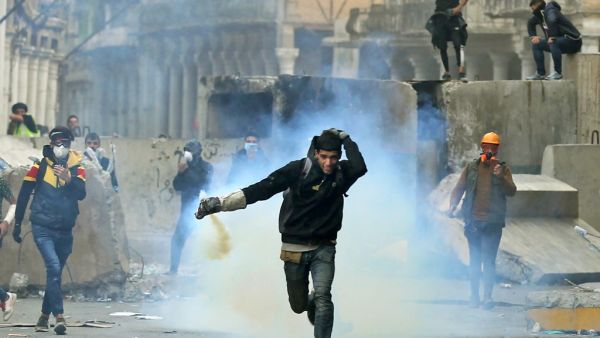 An Iraqi demonstrator runs for cover from teargas fired by Iraqi security forces in Baghdad's al-Rasheed street near al-Ahrar bridge on November 25, 2019, during ongoing anti-government demonstrations. (AFP/ File Photo)