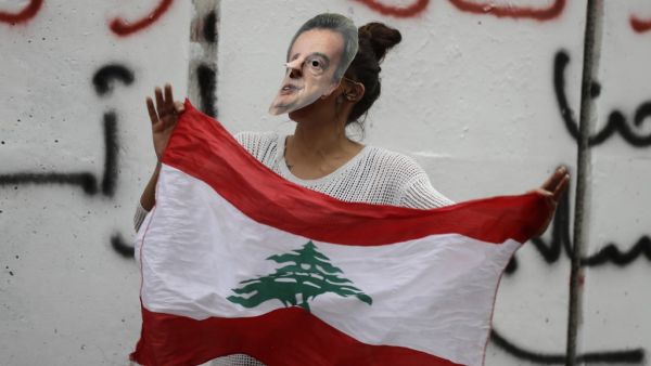 A Lebanese anti-government protester hold a mask of Lebanon's Central Bank Governor Riad Salameh during a protest in front of the central bank headquarters in Beirut to protest against the economic policies of the bank on November 27, 2019. (AFP/ File Photo)
