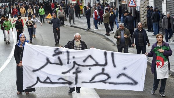 People march with a large banner reading in Arabic "Algeria is a red line" during a demonstration in the centre of the capital Algiers on November 30, 2019, in support of the upcoming presidential vote scheduled to take place in less than two weeks. (RYAD KRAMDI / AFP)