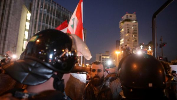 A Lebanese anti-government protester faces riot police on the eastern end of the Ring bridge that connects the western and eastern neighbourhoods of the capital Beirut on December 4, 2019. AFP