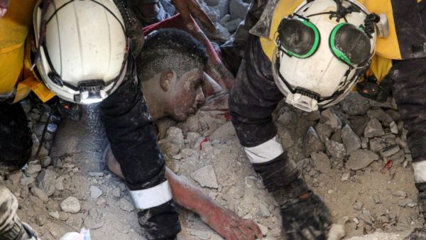 Members of the Syrian Civil Defence, also known as the White Helmets, rescue a survivor from the rubble of a collapsed building following a reported air strike in the village of Balyun in Syria's northwestern Idlib province on December 7, 2019. Syrian regime and Russian air strikes on December 7 killed over a dozen civilians, including children, in the country's last major opposition bastion of Idlib, the Syrian Observatory for Human Rights said. Abdulaziz KETAZ / AFP