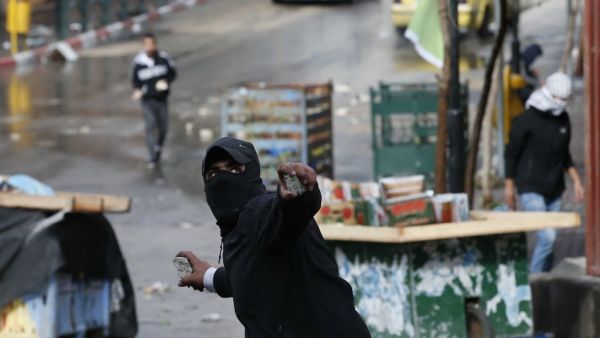 A Palestinian protester hurls stones during clashes with Israeli security forces in the southern West Bank city of Hebron, on December 9, 2019, amid a general strike over Israeli settlement activity. AFP