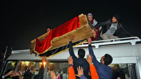 Mourners unload from the top of a bus a coffin draped in the Iraqi national flag in the central holy shrine city of Najaf on December 13, 2019, during the funeral of a teenager who was lynched and killed the previous day in Baghdad, as he was accused of attacking a protest encampment. (AFP/ File Photo)