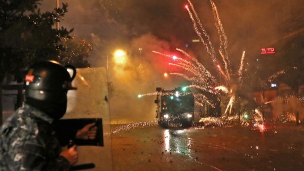 Supporters of Lebanon's Shiite Hezbollah and Amal groups hurl fireworks at security forces early on December 17, 2019 in central Beirut. Lebanon's president yesterday postponed consultation to select a new prime minister after weeks of largely peaceful street protests descended into weekend violence. ANWAR AMRO / AFP