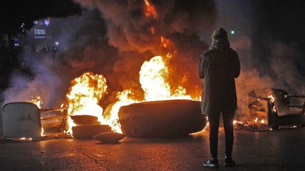 A protester stands by a flaming roadblock in the southern Lebanese city of Sidon early on December 17, 2019. Mahmoud ZAYYAT / AFP