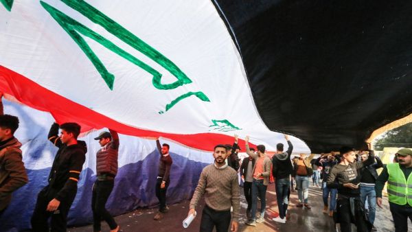 Protesters march with a giant Iraqi national flag during an anti-government demonstration in the capital Baghdad's central Tahrir Square on December 22, 2019.  SABAH ARAR / AFP