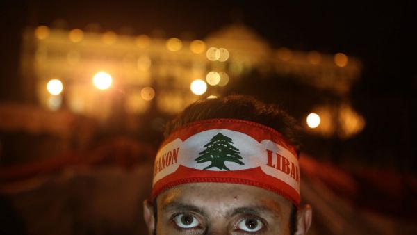 A Lebanese anti-corruption protester, his forehead wrapped with the national flag, poses in front of the Grand Serail (government building) during a protest in downtown Beirut on December 22, 2019. Demonstrators are demanding an overhaul of the political establishment which they deem corrupt and inept, insisting on a government of independents and experts with no ties to the country's sectarian parties. PATRICK BAZ / AFP