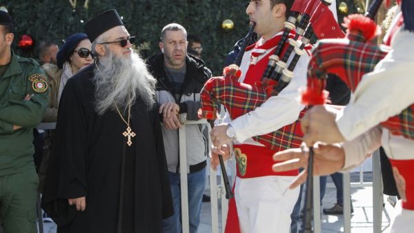 A priest looks at Palestinian scouts performing during a parade at the Manger Square outside the Church of the Nativity in the biblical West Bank city of Bethlehem on December 24, 2019. Pilgrims from around the world gathered today in the biblical city of Bethlehem, revered by Christians as the birthplace of Jesus, to celebrate Christmas in the Holy Land. Musa AL SHAER / AFP