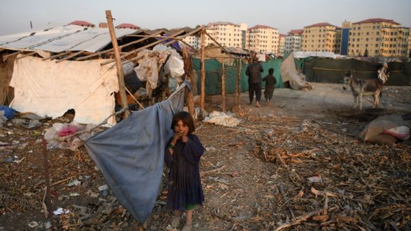 An internally displaced Afghan girl stands outside a temporary home at a refugee camp in Kabul on December 24, 2019. FARSHAD USYAN / AFP