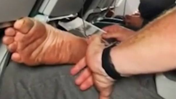 He is using the little finger of his left hand to scrape the thin layer of muck off the side of his heel. (Video Screenshot)