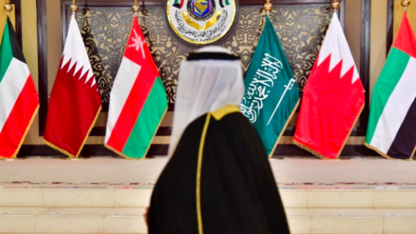 A man walks past the flags of the countries attending the Gulf Cooperation Council summit at Bayan palace in Kuwait City on 5 December (AFP)