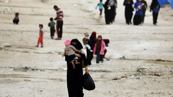 People walk through Ain Issa, one of the camps that holds displaced Syrians as well as foreign wives of ISIS fighters and their children. Thousands of foreign women and children languish in shelters in northeastern Syria, unwanted by their home governments and with no clear future. Delil Souleiman/AFP/Getty Images