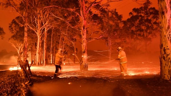 This timed-exposure image shows firefighters hosing down trees as they battle against bushfires around the town of Nowra in the Australian state of New South Wales on December 31, 2019. Thousands of holidaymakers and locals were forced to flee to beaches in fire-ravaged southeast Australia on December 31, as blazes ripped through popular tourist areas leaving no escape by land. Saeed KHAN / AFP