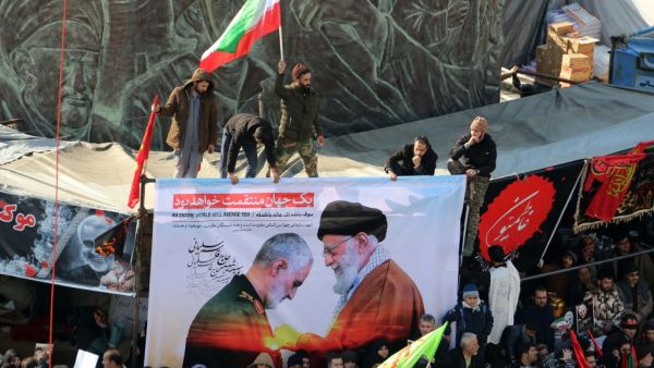 Iranian mourners carry a picture of Iran's Supreme Leader Ayatollah Ali Khamenei (R) granting the Order of Zolfaghar, the highest military honour of Iran, to General Qasem Soleimani, during the latter's funeral procession in the capital Tehran on January 6, (AFP/ File Photo)
