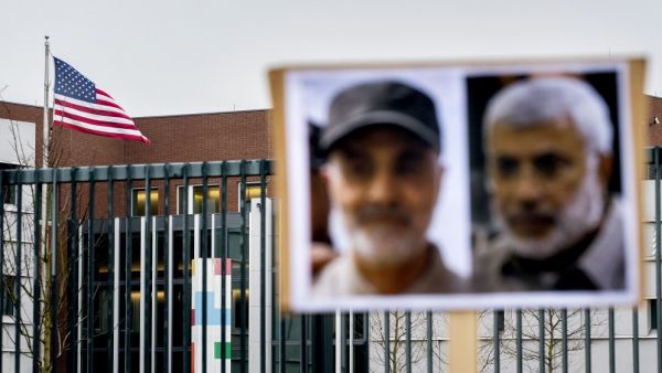 A picture shows the US flag and portraits of Iranian commander Qasem Soleimani (L) and Iraq's Hashed al-Shaabi military network deputy chief Abu Mahdi al-Muhandis, both killed in Baghdad early on January 3, 2020, by a US airstrike, as seen on a protesters' placard outside the US Embassy in The Hague on January 7, 2020. Koen Van WEEL / ANP / AFP
