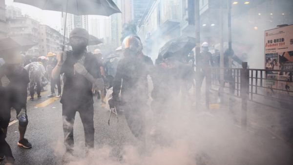 In this picture taken on August 25, 2019, Abby (centre R), 19, and her boyfriend Nick (centre L, holding tongs), 20, react after police fired tear gas during a protest in Tsuen Wan, an area in the New Territories in Hong Kong. ANTHONY WALLACE / AFP