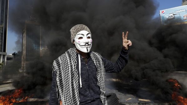 Lebanese anti-government protester flashes the victory sign in front of a burning roadblock during a demonstration in Beirut on January 14, 2020. (AFP/ File Photo)