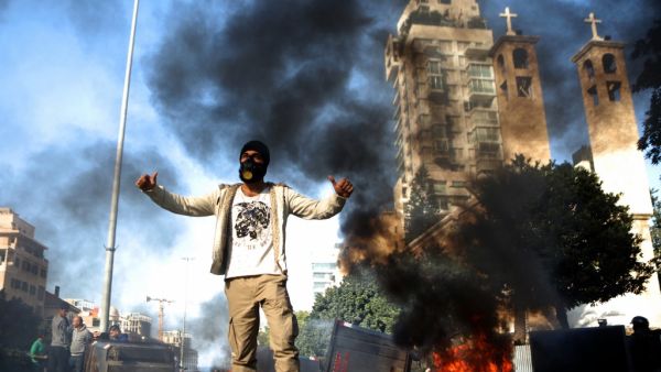 A Lebanese anti-government protester gestures next to burning garbage bins set up to block a road in the capital Beirut, on January 14, 2020. Lebanese protesters resumed blocking major highways in what they said would be a "week of wrath" demanding an end to a nearly three-month political vacuum. Although protests had declined in size in recent weeks, demonstrations have been ongoing since October, increasingly targeting banks and state institutions blamed for driving the country towards collapse. PATRICK B