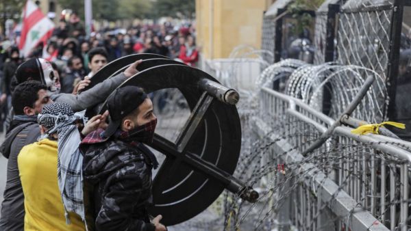Anti-government protesters attempt to break through the security barrier in the central downtown district of the Lebanese capital Beirut near the parliament headquarters during clashes with security forces on January 18, 2020. ANWAR AMRO / AFP
