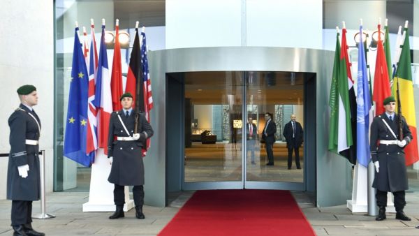 Guards stand next to the flags of the participating countries at the entrance of the German Chancellery in Berlin on January 19, 2020, before the arrival of the participants of the Peace summit on Libya. John MACDOUGALL / AFP