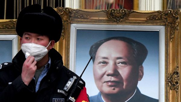 A security guard wearing a facemask to help stop the spread of a deadly virus which began in Wuhan, stands beside a portrait of the late Chinese communist leader Mao Zedong at a shopping centre in Beijing on January 27, 2020. (AFP/ File Photo)