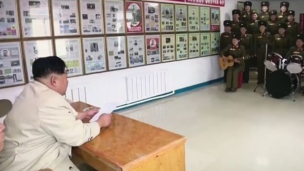 Spectator: North Korean strongman Kim Jong-un sits behind a desk and watches the performance by women in military uniform. (Video Screenshot)
