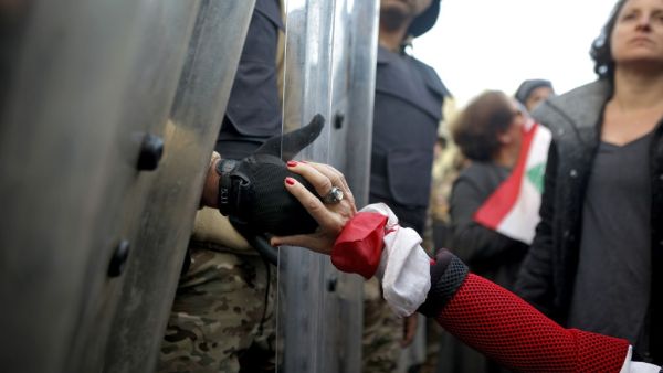 A Lebanese anti-government protester holds the hand of a Lebanese army soldier as she blocks a road leading to the parliament in the capital Beirut's downtown district on January 27, 2020. PATRICK BAZ / AFP