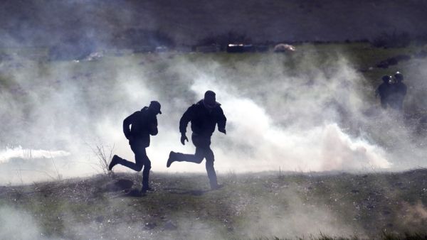 Palestinian protesters run for cover amid clashes with Israeli troops during a demonstration against a US brokered Middle East peace plan, near the West Bank village of Tamun near the Jordan Valley on January 31, 2020. AFP